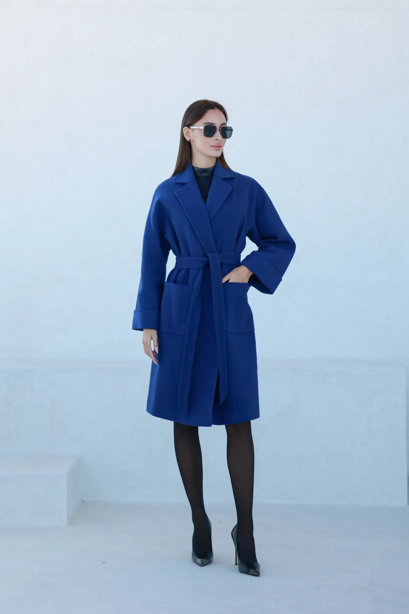 Royal blue wool coat with black belt and cuffs, oversized sunglasses.